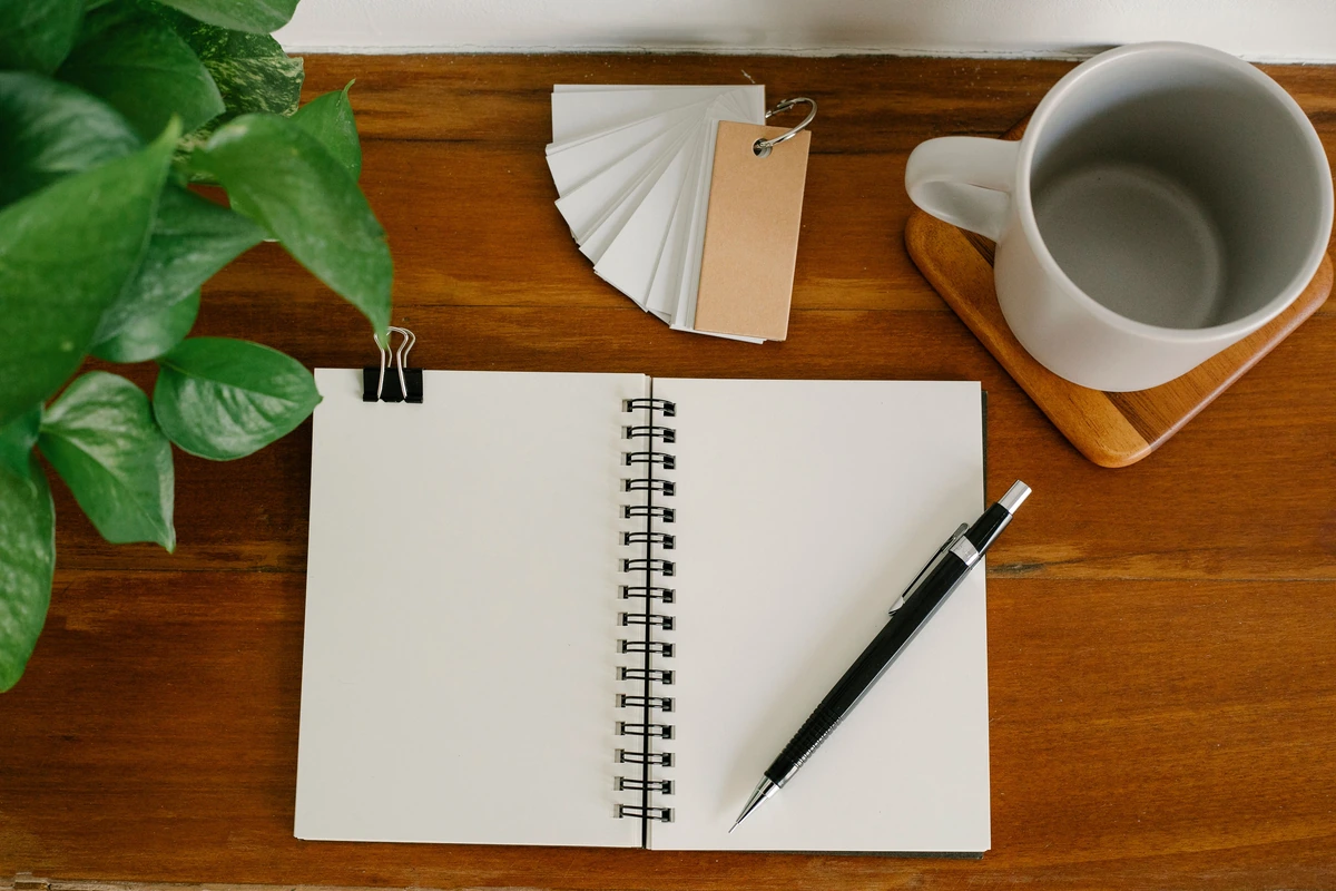 Carnet à spirale ouvert, stylo et tasse de café sur un bureau en bois