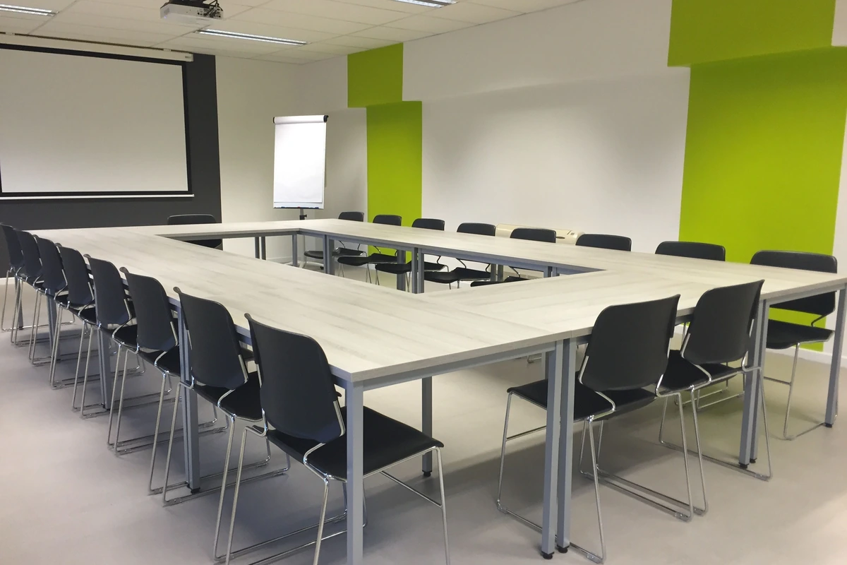 Salle de formation vide disposée en U avec tableau blanc et paperboard