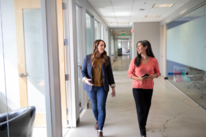 Deux collègues marchant côte à côte dans un couloir de bureau lumineux